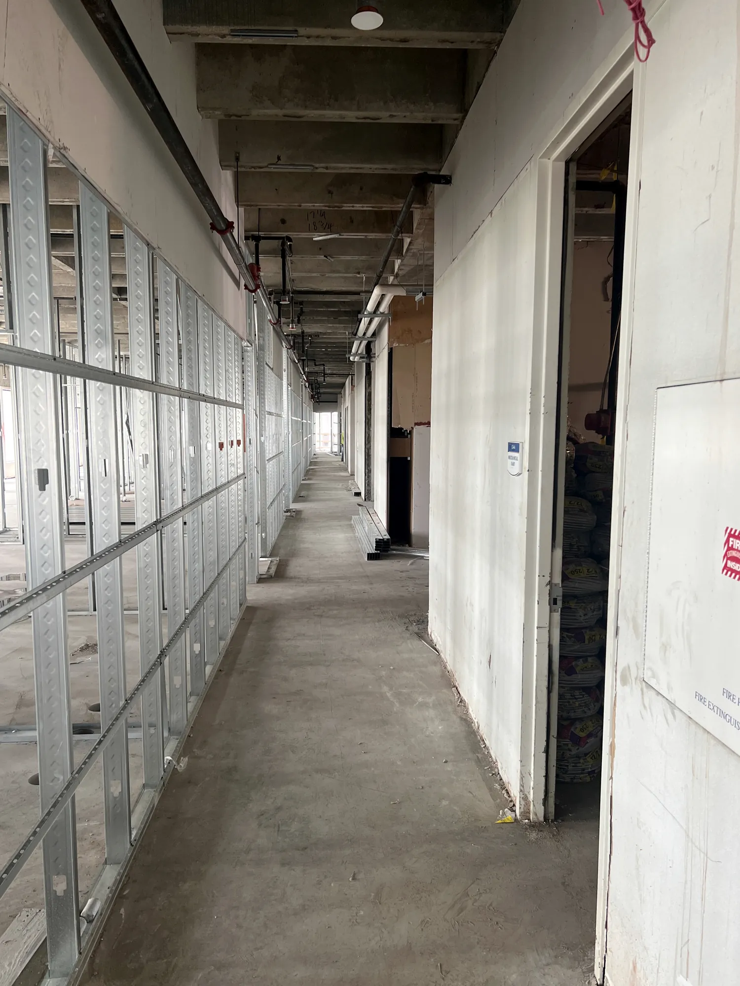Hanging drywall on framed corridor walls at Elev8 Luxury Apartments