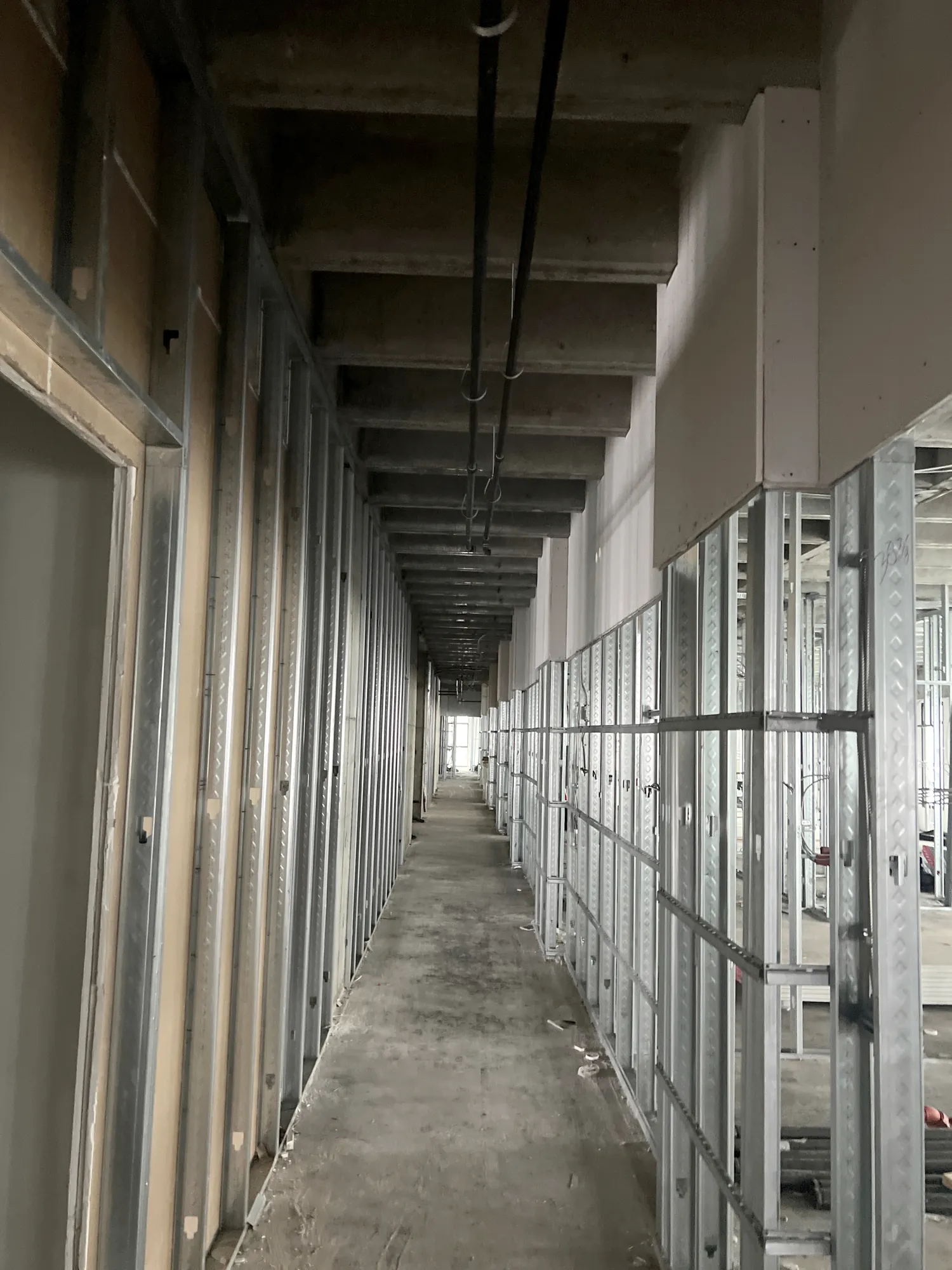 Metal stud framing installation along a residential corridor at Elev8 Luxury Apartments