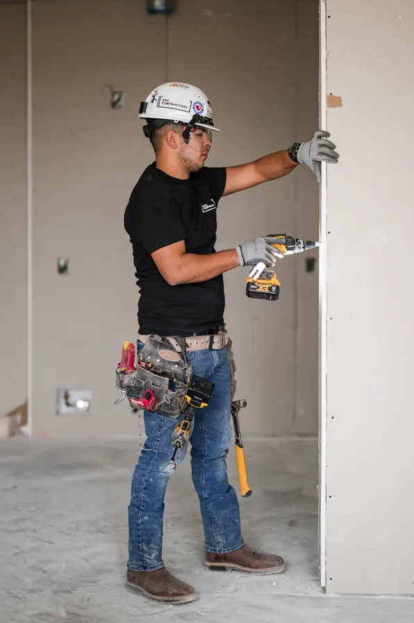 contractor-drilling-wall Contractor drilling a section of drywall
