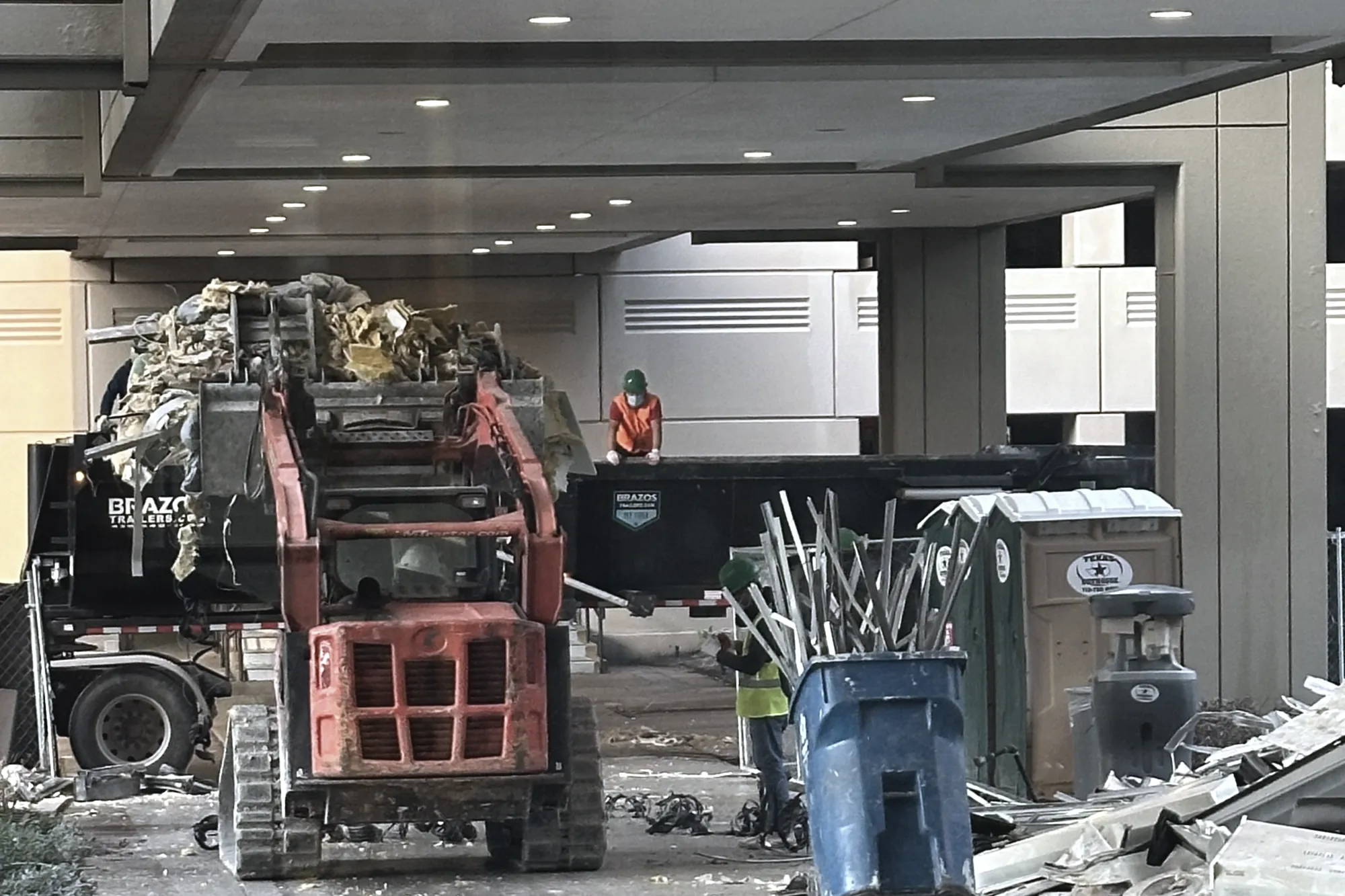 The Watt at Westlake — demolition debris load-out at grade, track loader and roll-off containers, crew in PPE